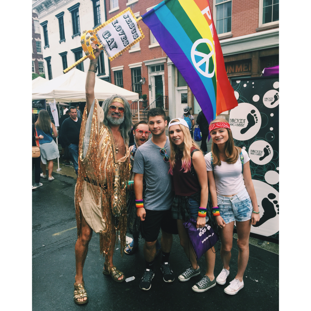 friends attending the new york city gay pride parade. Holding a rainbow peace flag